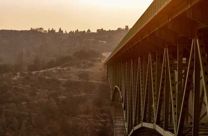 shutterstock_1874180248 Steel truss bridge spanning a canyon at sunset