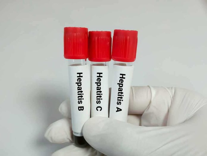 Gloved hand holding three blood sample tubes with red caps