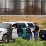 Marine Base BREACHED — Then It Gets WEIRD law enforcement officers confer beside patrol vehicles near a border fence