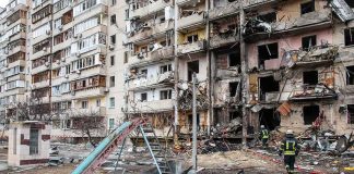 Damaged apartment building behind a playground slide