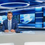 News anchor at a modern television studio desk