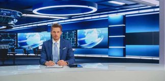 News anchor at a modern television studio desk