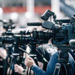 1,000 Babies – The Explosive ‘Birth Tourism’ Revelation Broadcast cameras on tripods at a press event