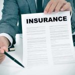 Person in suit holding an insurance document and a pen