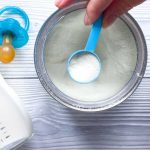 Baby formula powder in a can with a blue scoop
