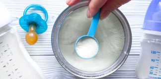 Baby formula powder in a can with a blue scoop