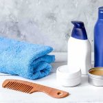 bathroom toiletries with blue towel and wooden comb on white surface