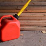 Red gasoline can with yellow spout on a garage floor