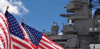 Trump Signed. Someone Was LOCKED OUT American flags in front of a naval ship under a blue sky