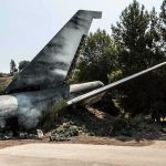 Wrecked airplane tail section beside a road