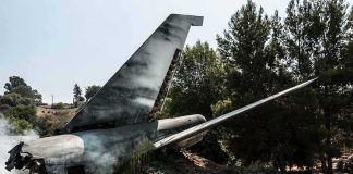 Wrecked airplane tail section beside a road