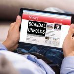 Person holding a tablet showing a news website
