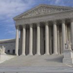 The Supreme Court building featuring large columns and statues