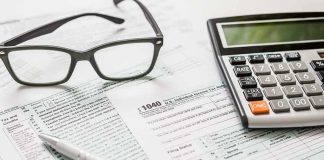 Tax forms with calculator, glasses, and pen