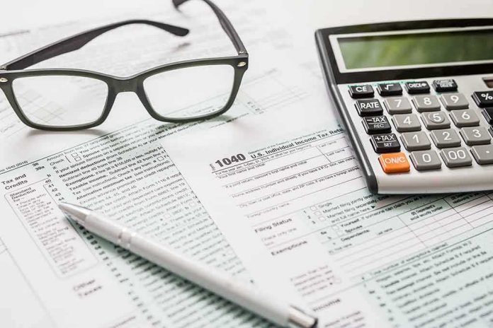 shutterstock_1011737299 Tax forms with calculator, glasses, and pen