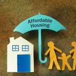 Paper cutouts of house and family under umbrella labeled affordable housing