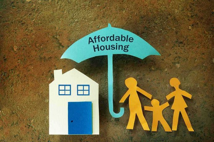 Paper cutouts of house and family under umbrella labeled affordable housing