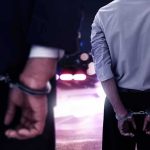 3 CUFFED In SICKENING Case — One Man’s PHONE Is The Kicker Two men in handcuffs with police lights in the background