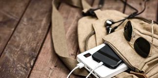 Beige backpack with phone charging on power bank and sunglasses