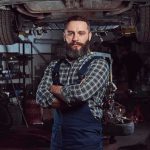 Trump RESCUES Mechanics From A ROTTEN Double Standard Auto mechanic standing with arms crossed in a garage