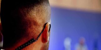 Security guard with earpiece watching a blurred event stage