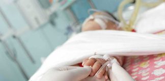 Baby Barely SURVIVED — Then Came The SCARIEST Part Gloved hands holding a baby's hand in a hospital bed