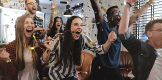 Group of friends cheering indoors with confetti flying