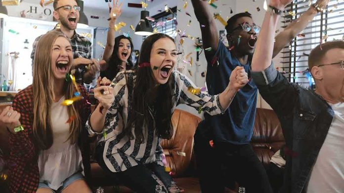 Group of friends cheering indoors with confetti flying