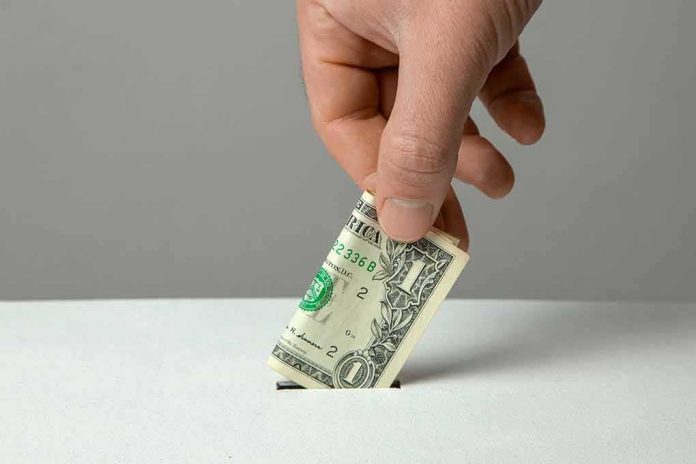 Hand inserting a folded dollar bill into a small slot