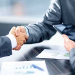 Businesspeople handshake at meeting table