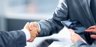 Businesspeople handshake at meeting table
