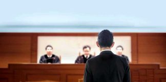 man in suit facing judges in a courtroom