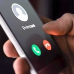 Hand holding smartphone with incoming unknown call screen