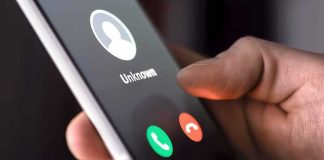 Hand holding smartphone with incoming unknown call screen