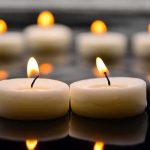 BELOVED Cartoon Voice DEAD At 46 Tealight candles with soft flames on a reflective surface