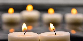 Tealight candles with soft flames on a reflective surface