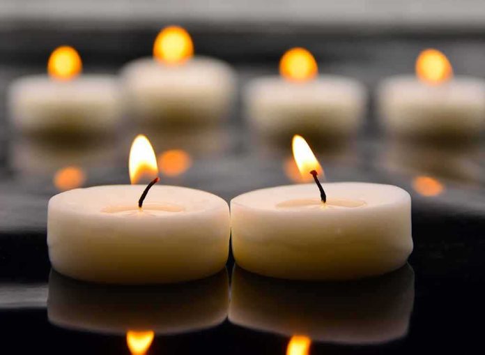 Tealight candles with soft flames on a reflective surface