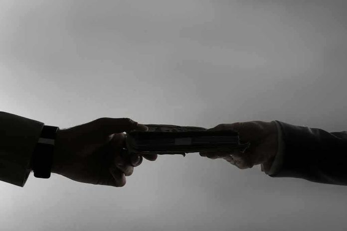 shutterstock_1667655304 Silhouetted hands exchanging a stack of cash