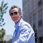 man in sunglasses wearing a light blue shirt outdoors