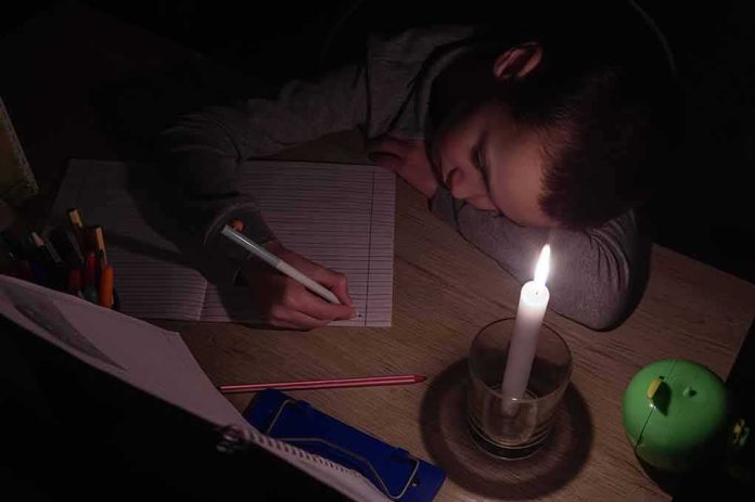Child doing homework by candlelight at a desk