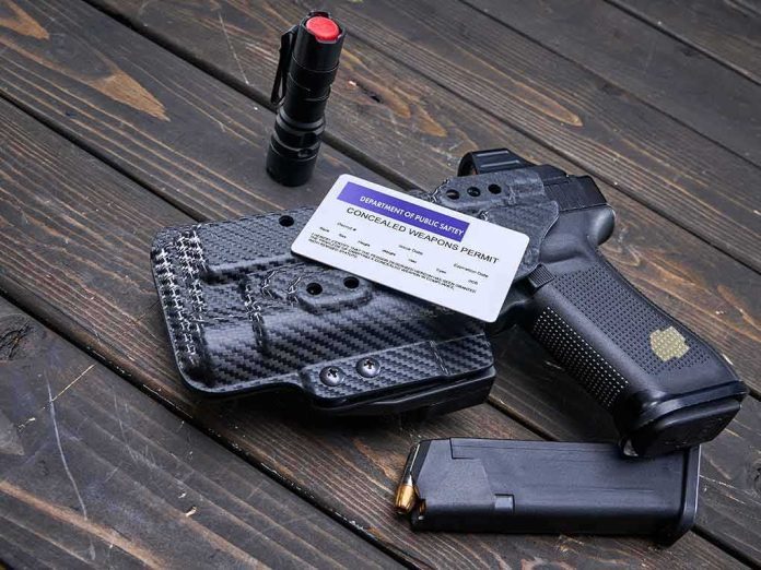 Handgun with holster, permit card, flashlight, and magazine on wooden surface