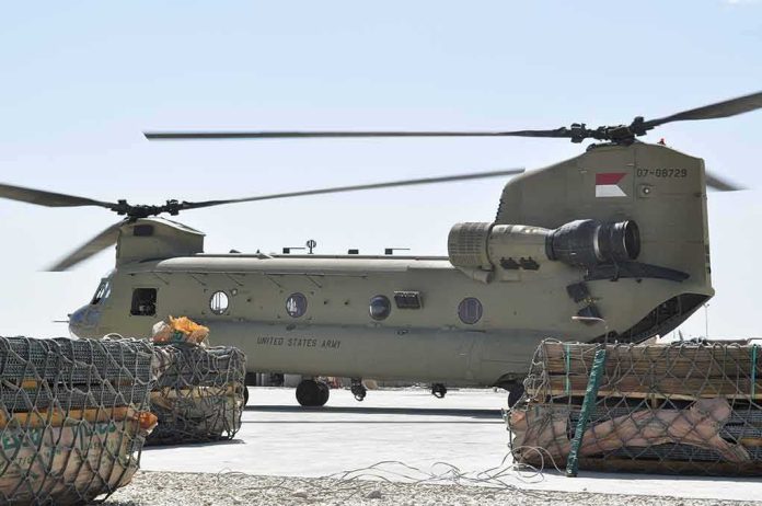 Chinook military helicopter on tarmac with cargo pallets