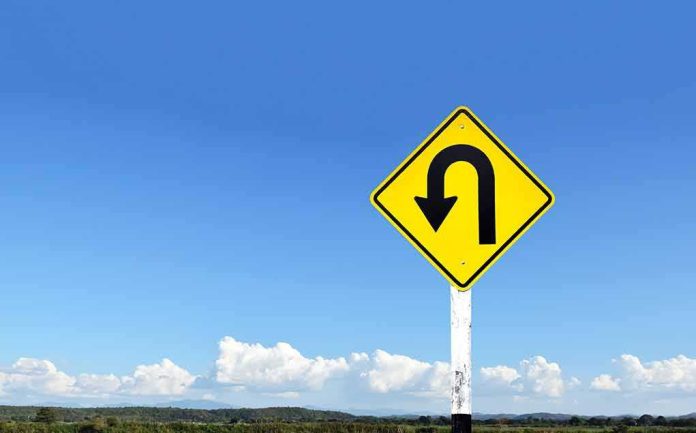 U-turn road sign against blue sky
