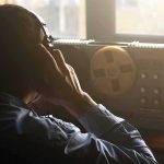 Person listening with headphones to a reel-to-reel tape recorder