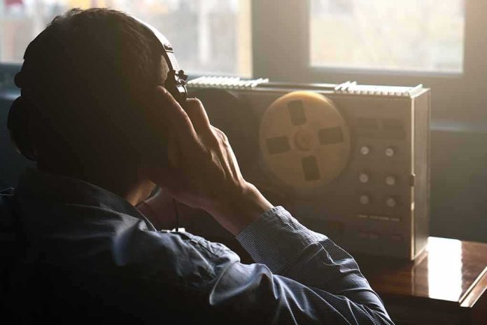 shutterstock_2141230189 Person listening with headphones to a reel-to-reel tape recorder