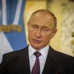 Vladimir Putin speaking at a podium with microphones