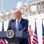 Putin Hands Trump What Biden Never Got Donald Trump speaking at a podium with American flags and a ship in the background
