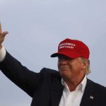 Donald Trump waving in a red cap