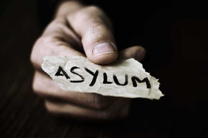 shutterstock_398319616-1 Hand holding torn paper with the word asylum