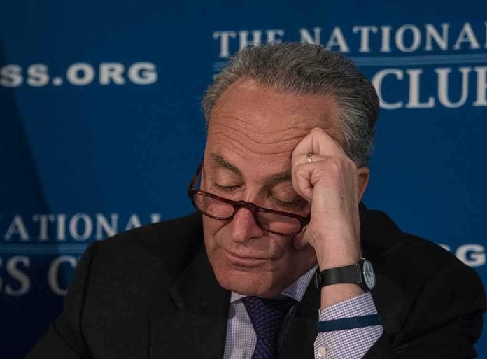 man with glasses resting forehead on hand at event podium